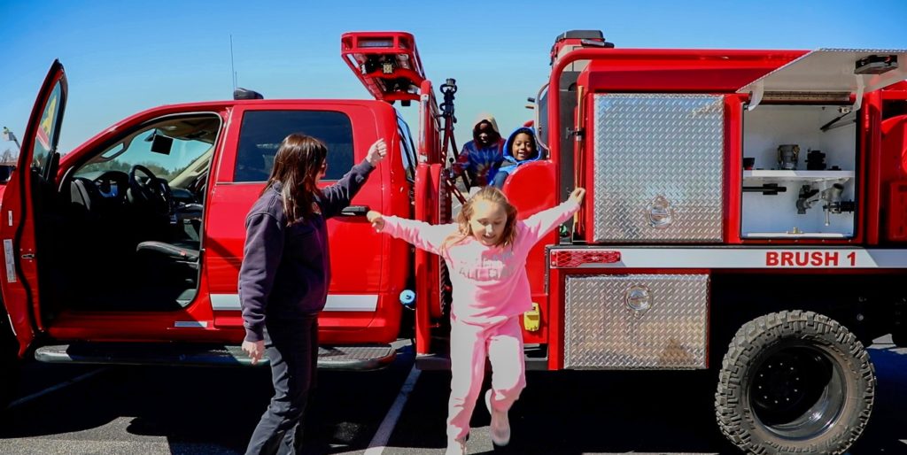 Girl in pink jumping from fire truck